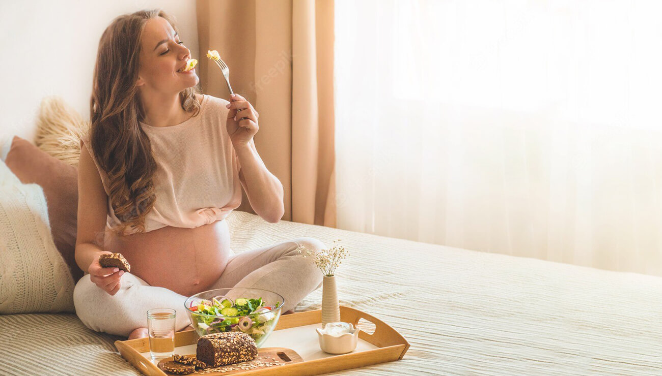 Mulher grávida comendo uma salada